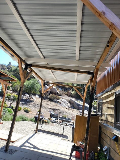 Up on the ladder, roofing the patio outside my tiny house!