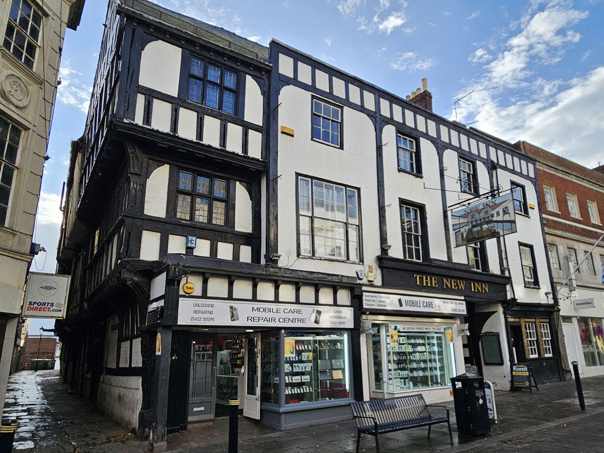 A three storey Tudor-style building on a high street, with mobile phone shops on the ground floor