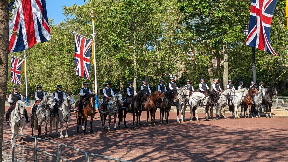 16 Mounted Police lined up across The Mall (central London) on brown or dappled grey horses, and the Union Jack flag flying with a background of trees. 16 Mounted Police lined up across The Mall (central London) on brown or dappled grey horses, and the Union Jack flag flying with a background of trees.