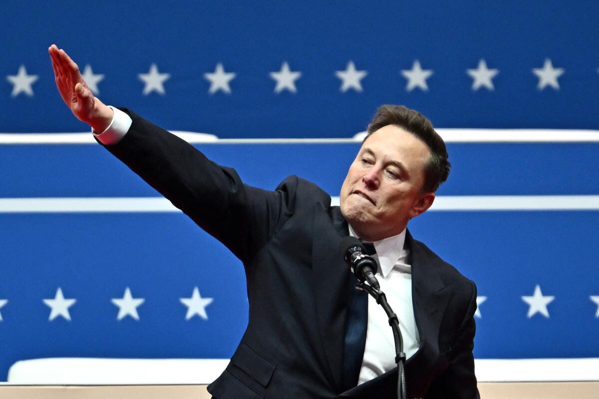 Elon Musk gestures with an outstretched arm.