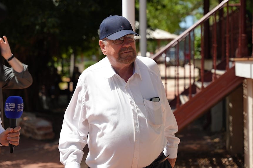 a man in a white shirt wearing a cap 