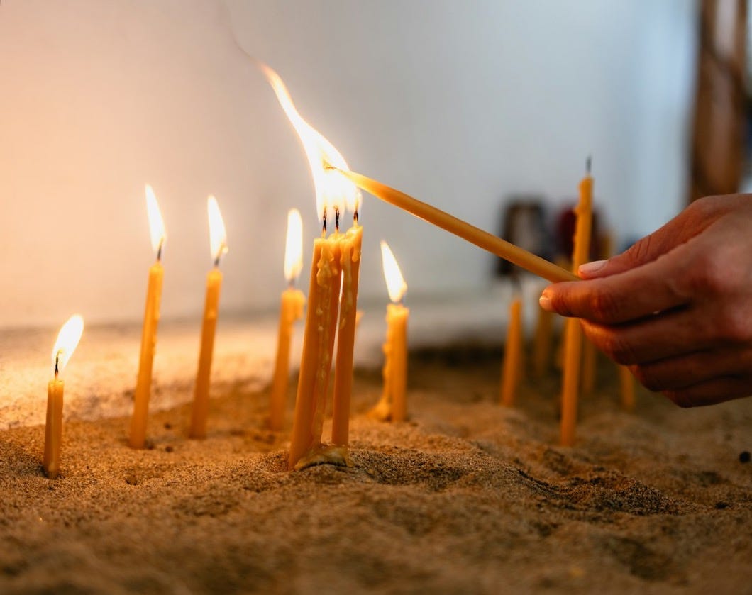 a person lighting a candle in the sand