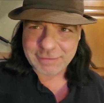 A man with long dark hair and a brown hat, wearing a dark shirt. Text overlay includes "THE SHIELD OF FAITH" with a quote and an armored figure holding a shield.