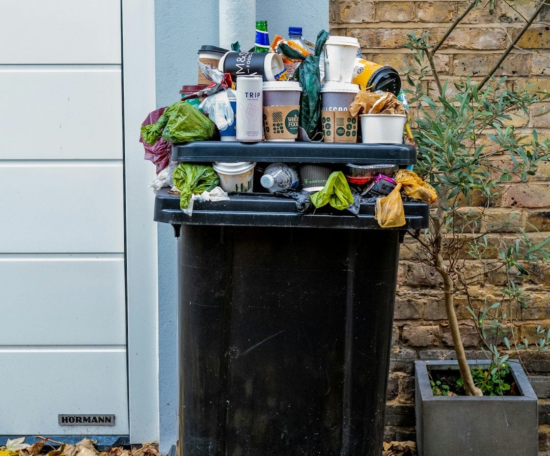 black trash bin with green leaves
