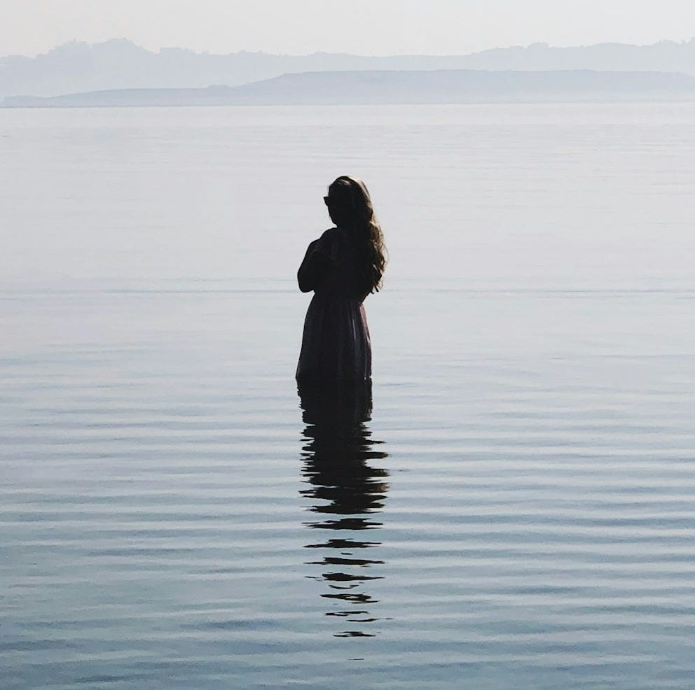 woman in black dress standing on water during daytime woman in black dress standing on water during daytime