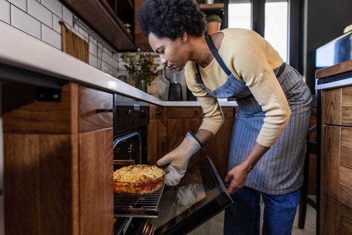 Latin-American woman is taking a homemade mac and cheese out of the oven. Domestic life.