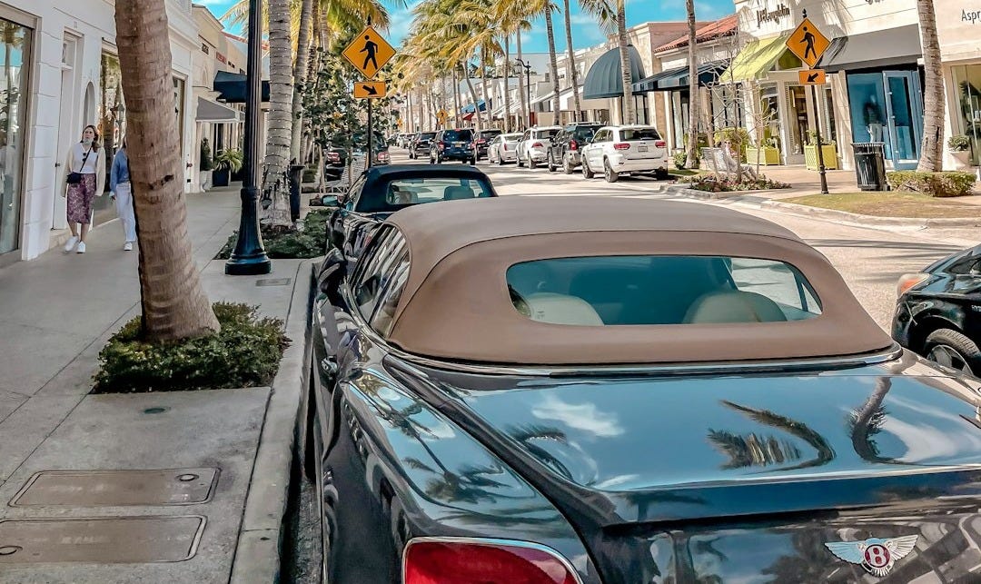 a street lined with palm trees and parked cars