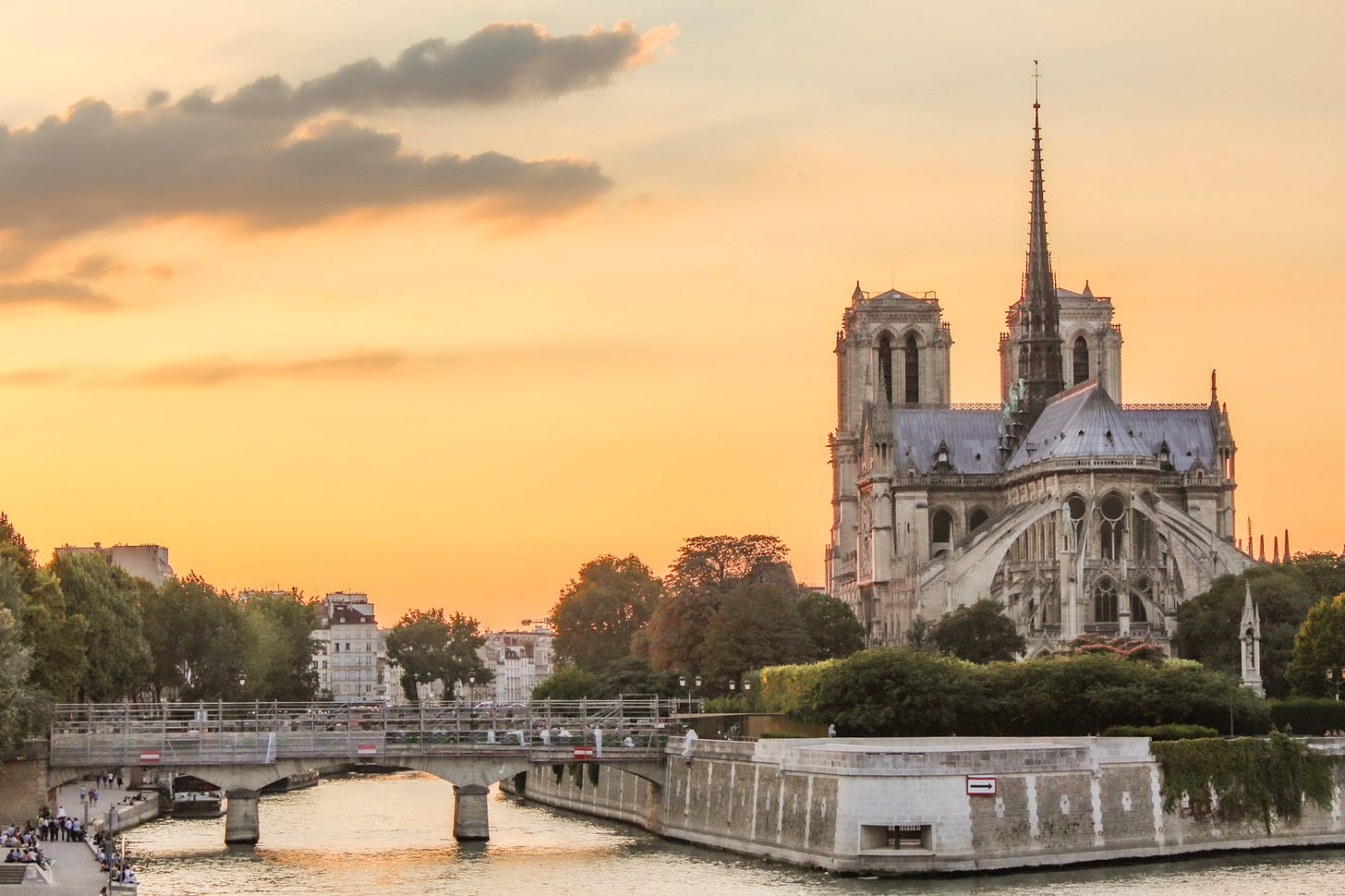 Sunset view of Notre-Dame Cathedral from Île Saint-Louis with the Seine glowing beneath the evening sky