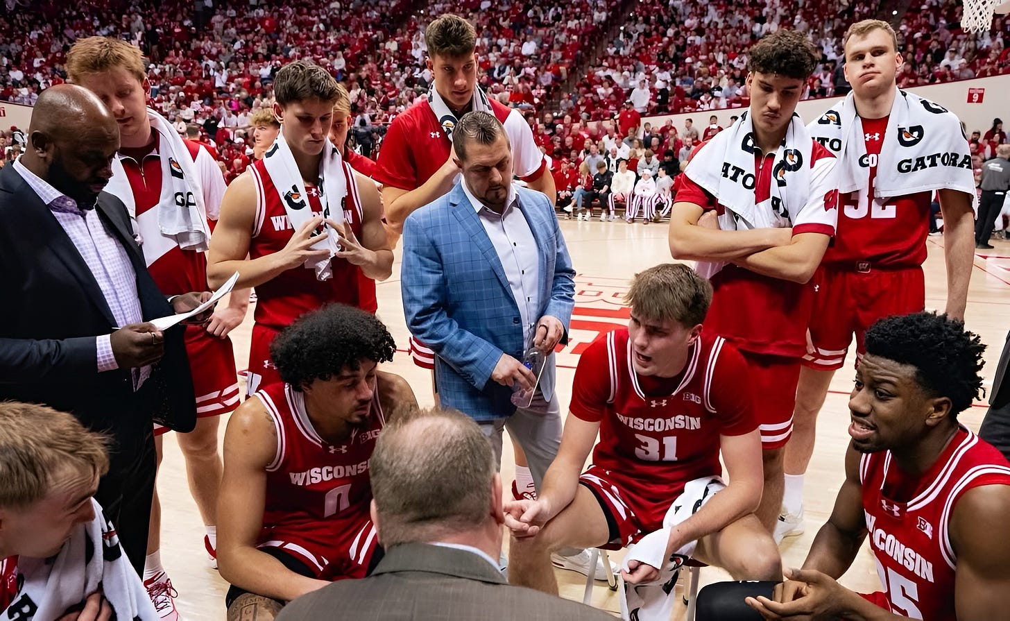 Wisconsin Badgers head coach Greg Gard speaking to players in a huddle during a timeout.