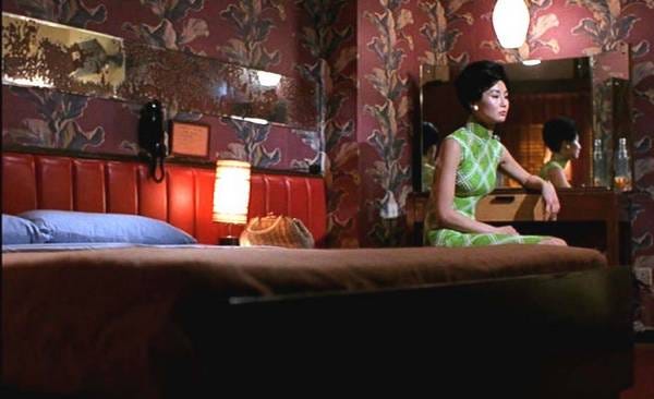 In the Mood for Love (2000); a still of Maggie Cheung sitting on a bed in a red room.