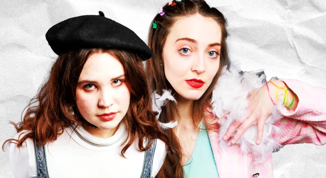 Two women posing - one wearing a beret and white jumper and one wearing a pink jacket and blue t-shirt Two women posing - one wearing a beret and white jumper and one wearing a pink jacket and blue t-shirt