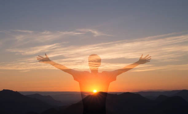 Faith and gratitude Man with arms raised with sunset in the mountains in the background. Person worshiping or thanking God. Success and happiness concept. emotional resilience stock pictures, royalty-free photos & images