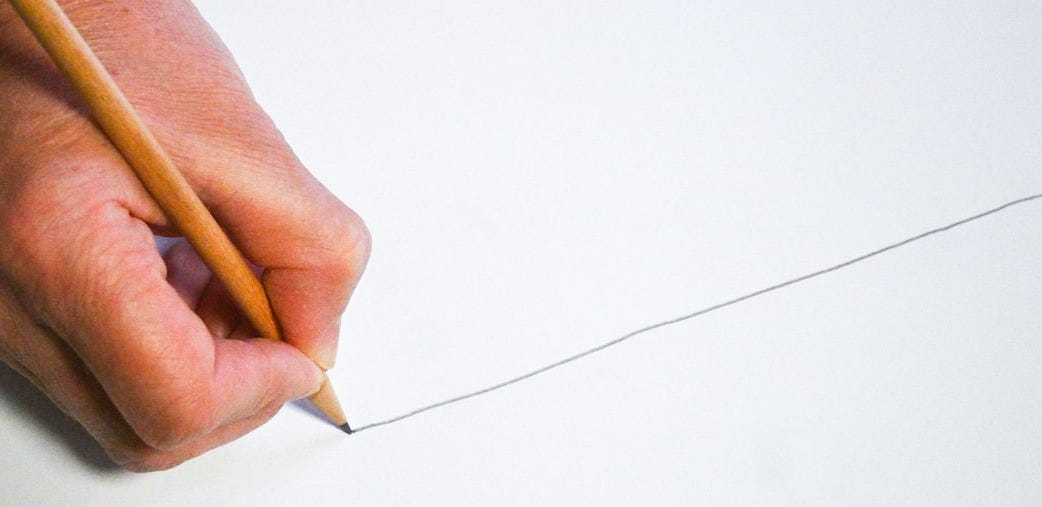 A person holding a pencil and writing on a piece of paper