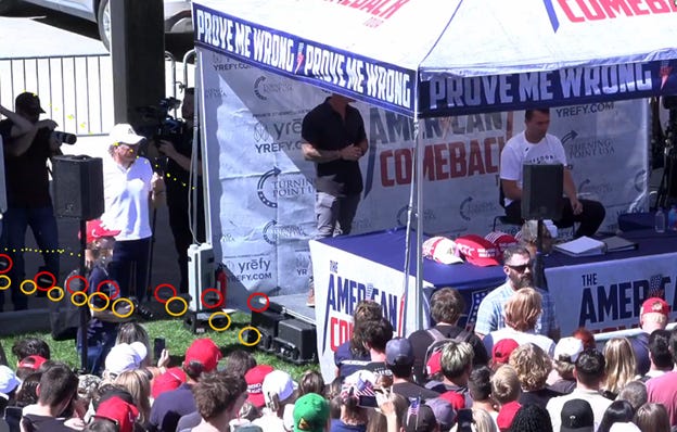 A person standing under a tent with a crowd of people watching

AI-generated content may be incorrect.