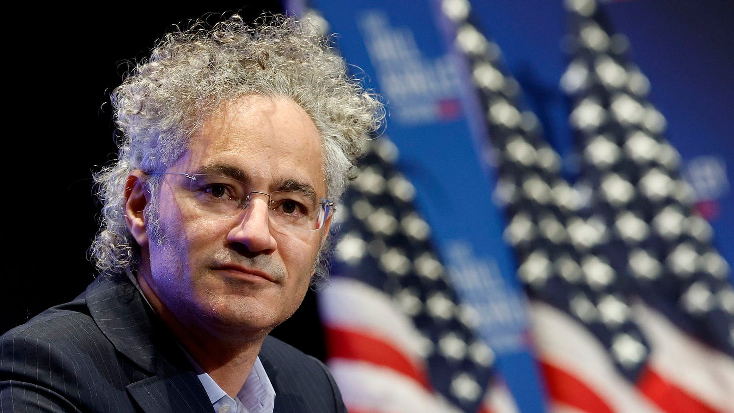 A photo of Palantir CEO Alex Karp with American flags in the background. 