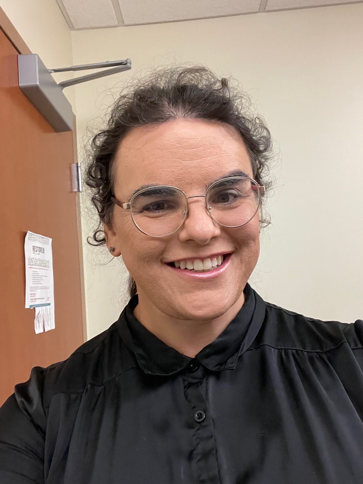 Me - not an AI-generated image, but genuinely me - smiling and wearing a black blouse.