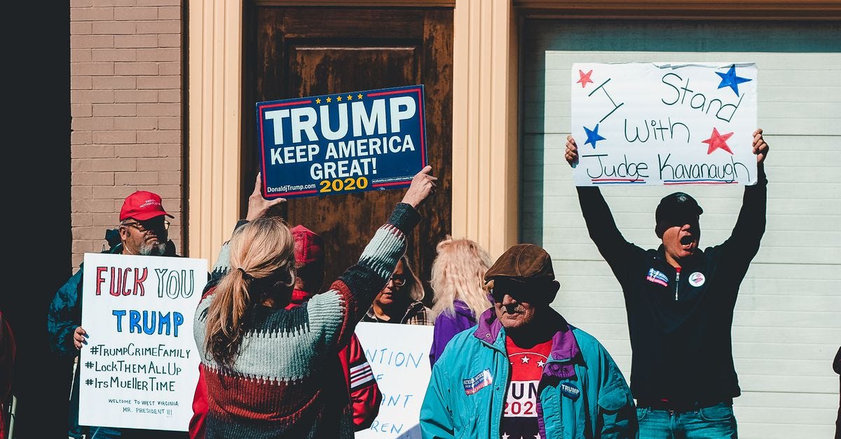 A group of people at a political rally in Wheeling, West Virginia, supporting different 2020 election campaigns.