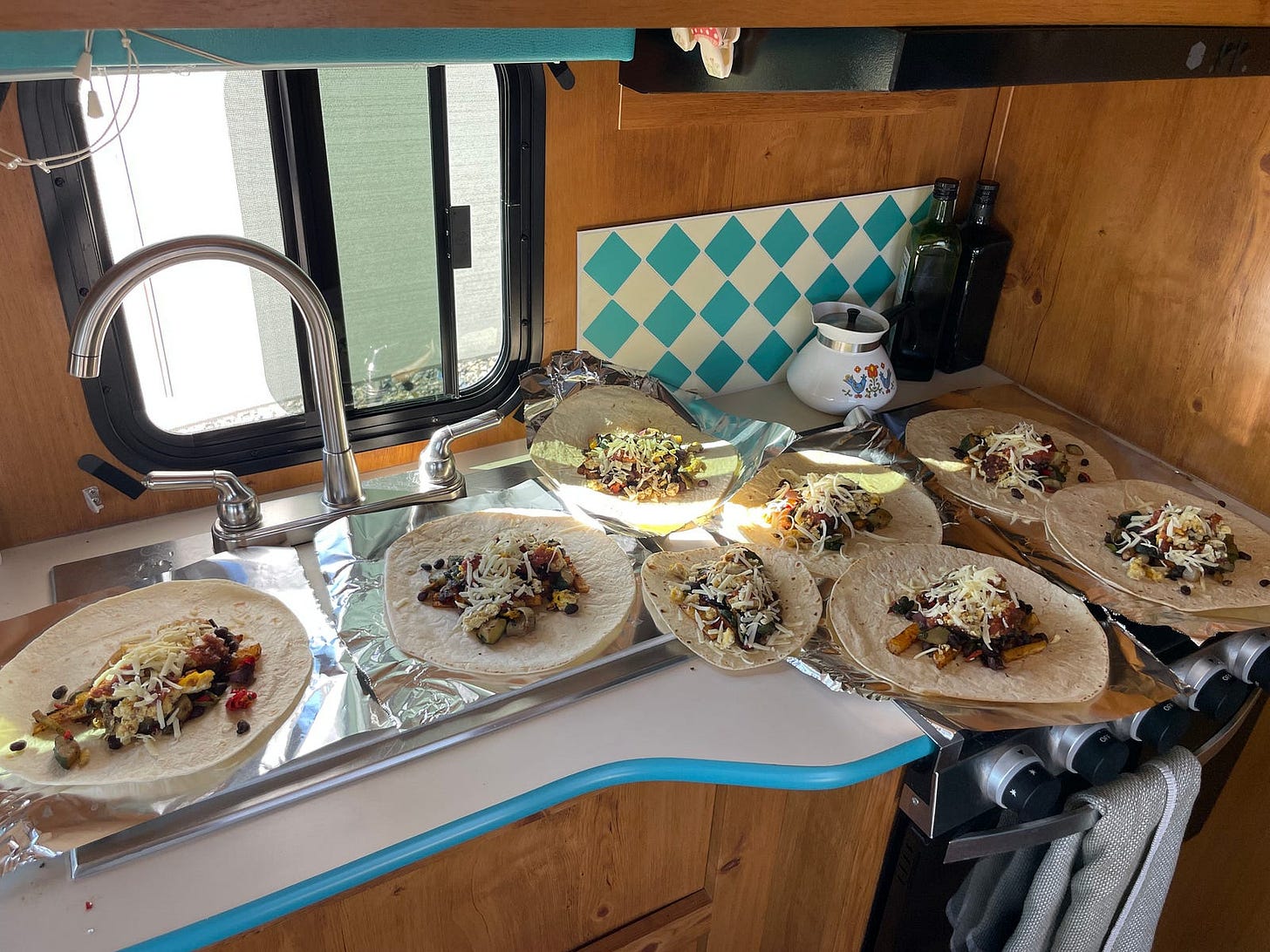 seven burritos laying on a counter top ready to get rolled up