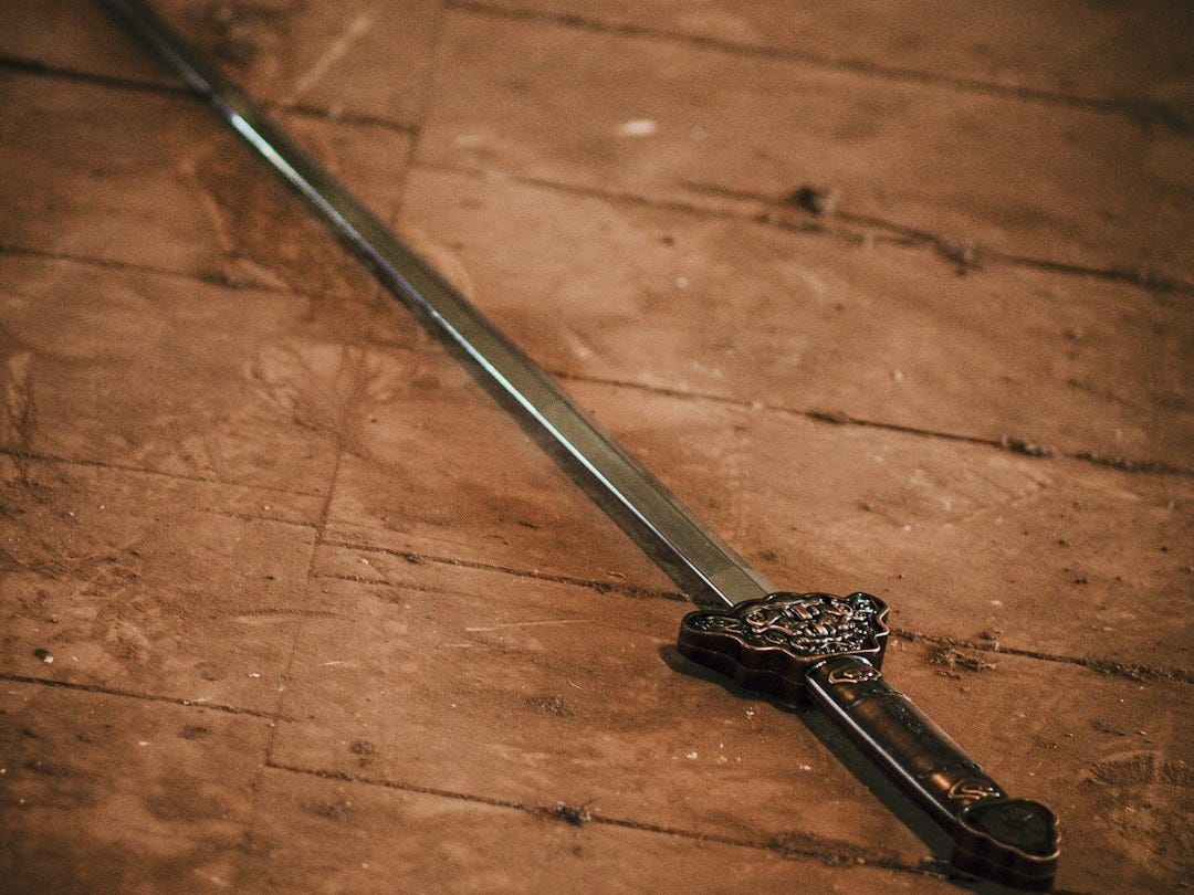 a sword laying on the ground on a wooden floor