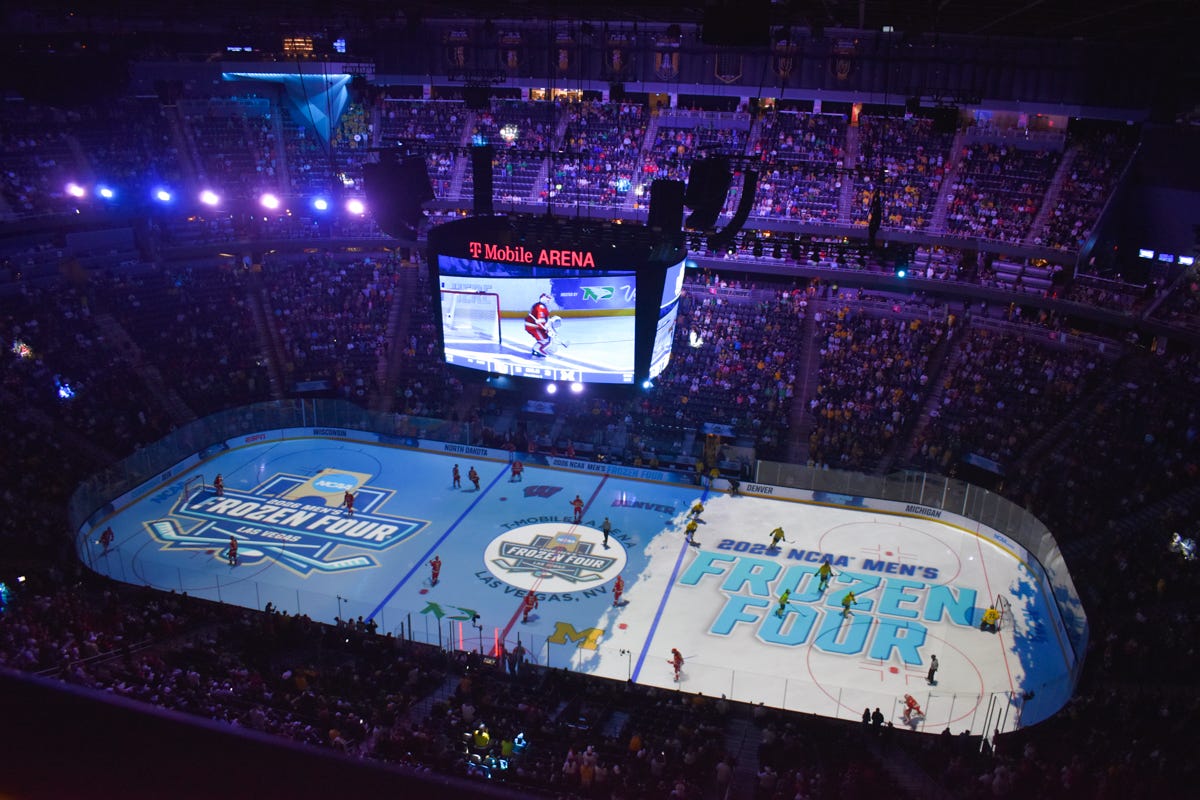 A zoomed-out shot before a game in the 2026 Frozen Four showing the full sheet of ice and fans in seats