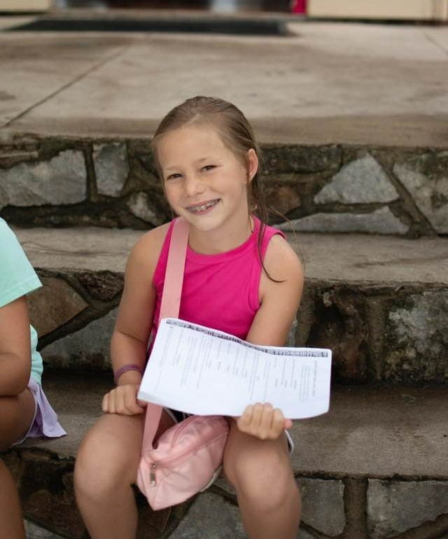 Girl sitting on steps holding papers.