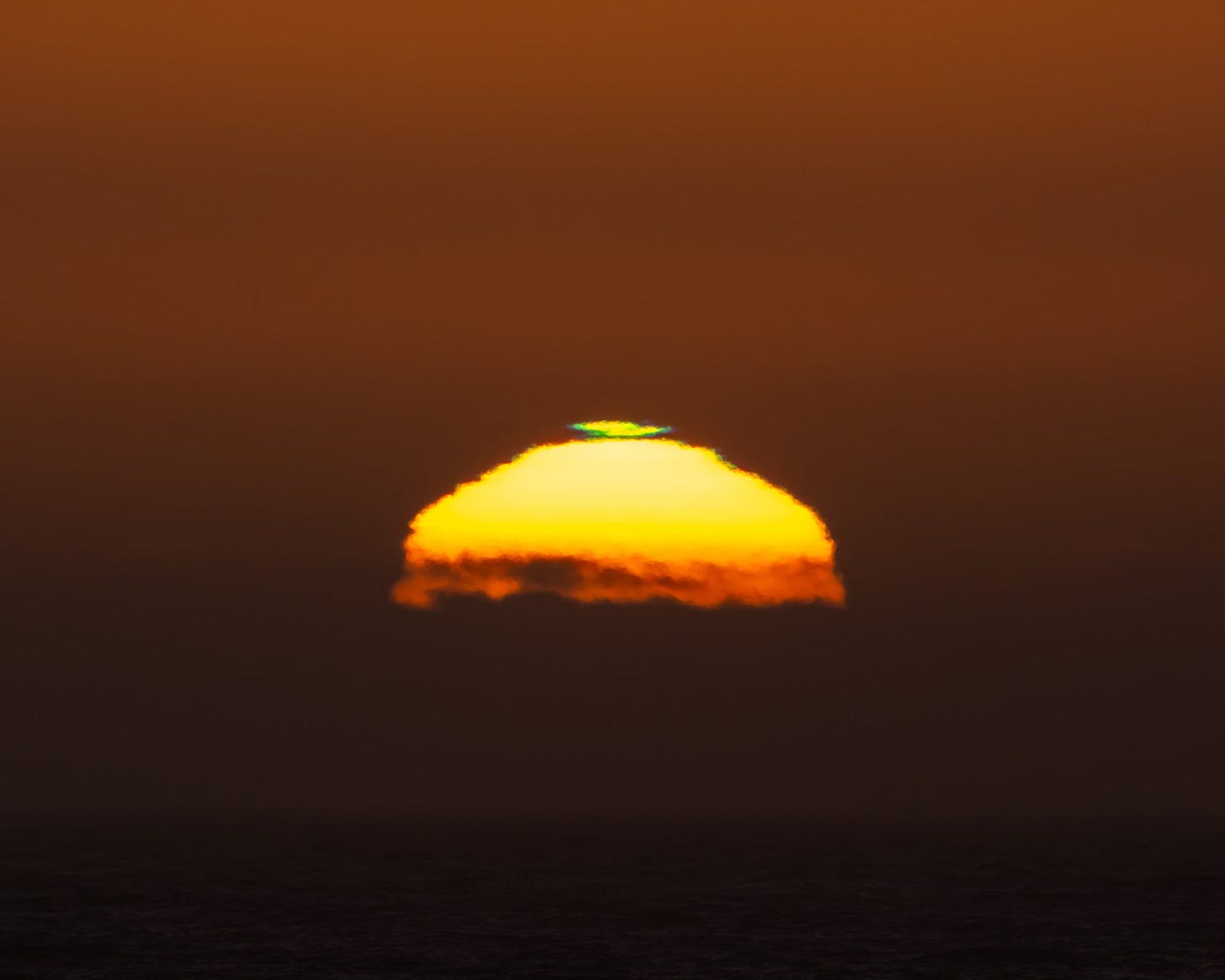 Sun setting on the Oregon Coast showing green flash on upper portion of the sun.