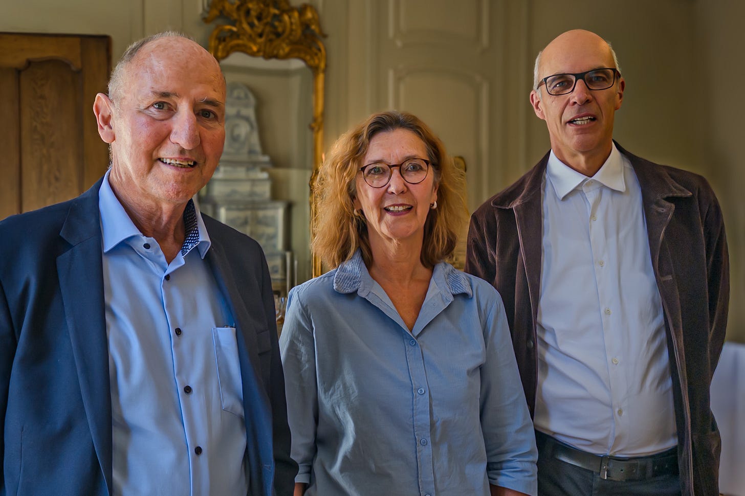 Urs Niggli, Eva Wyss und Christof Dietler stehen nebeneinander in einem historischen Innenraum: links Niggli im dunklen Sakko, in der Mitte Wyss mit Brille und hellblauer Bluse, rechts Dietler mit Brille, weissem Hemd und dunkler Jacke. Im Hintergrund sind ein verzierter Spiegel und ein historischer Kachelofen zu sehen. Urs Niggli, Eva Wyss und Christof Dietler stehen nebeneinander in einem historischen Innenraum: links Niggli im dunklen Sakko, in der Mitte Wyss mit Brille und hellblauer Bluse, rechts Dietler mit Brille, weissem Hemd und dunkler Jacke. Im Hintergrund sind ein verzierter Spiegel und ein historischer Kachelofen zu sehen.