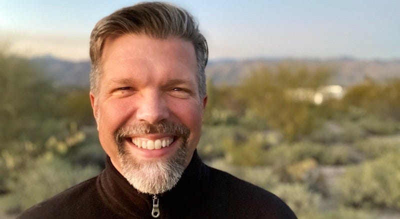 Reed Dickson smiling in the Tucson desert, the Catalina mountains behind him.