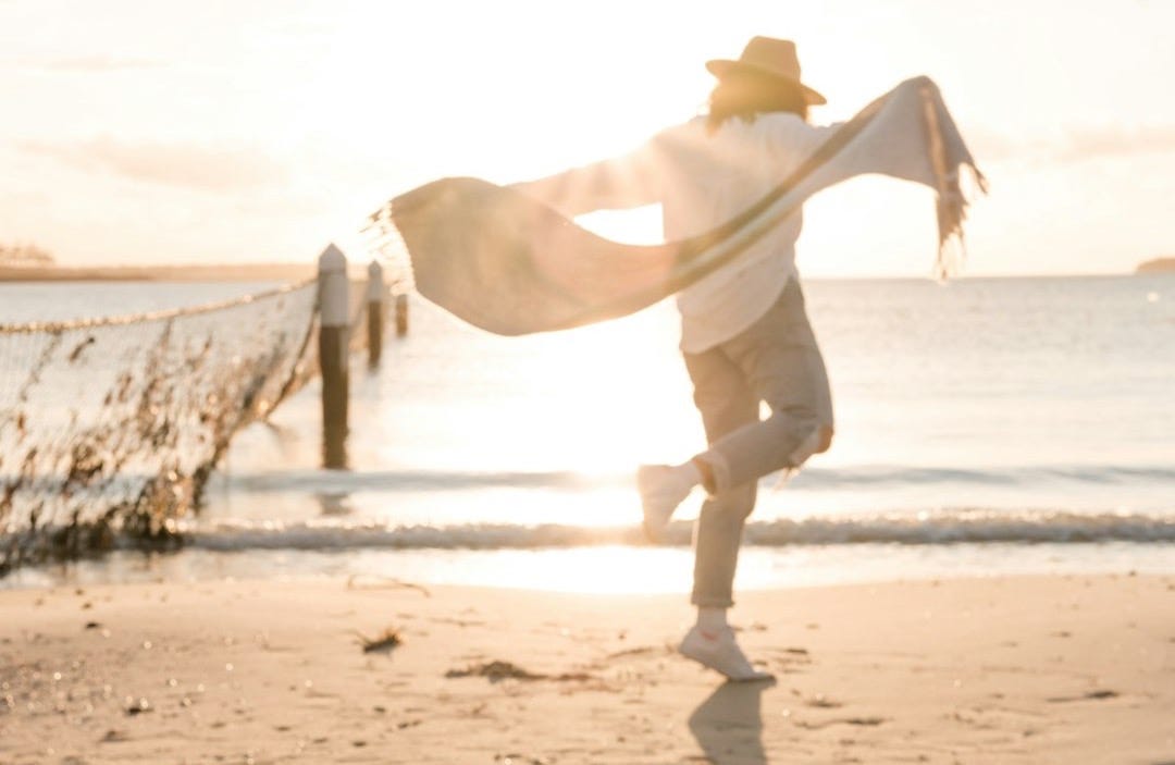 person in white sport shirt on shore during golden hour