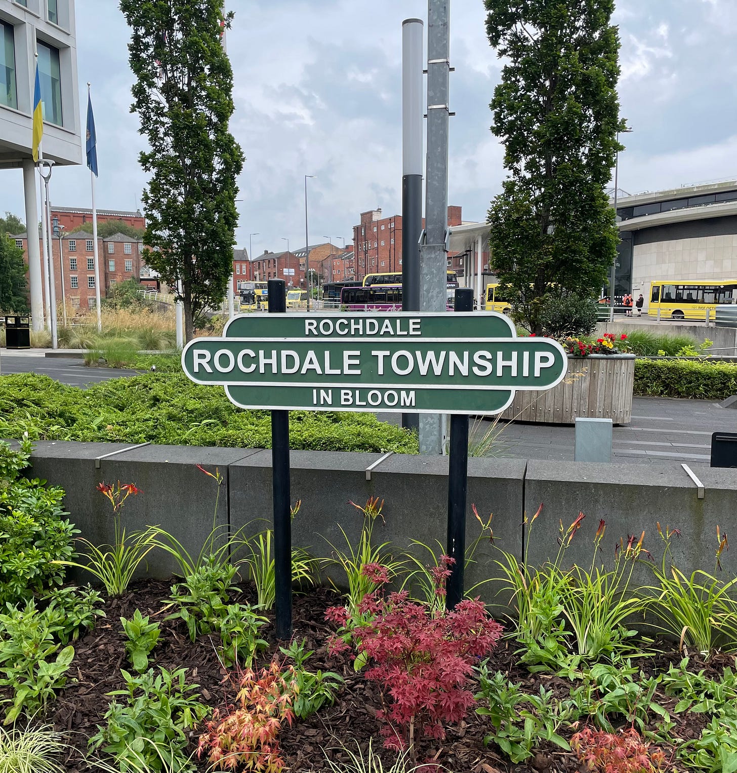 A railway-style sign surrounded by plants and flowers proclaiming that this is Rochdale Township and it is In Bloom.