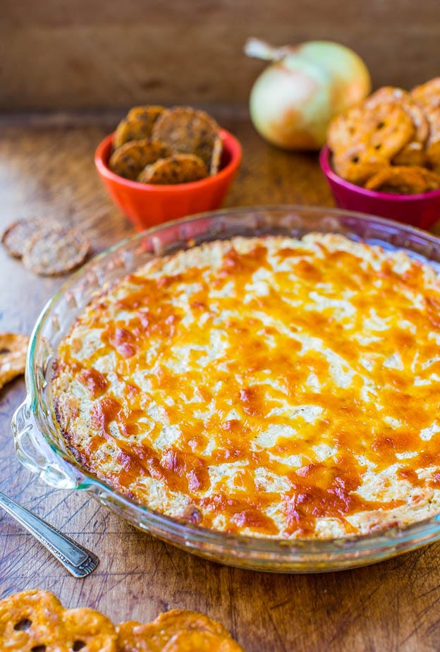 A freshly baked cheese and salsa dip in a glass pie dish, accompanied by an assortment of crackers and snacks. A freshly baked cheese and salsa dip in a glass pie dish, accompanied by an assortment of crackers and snacks.