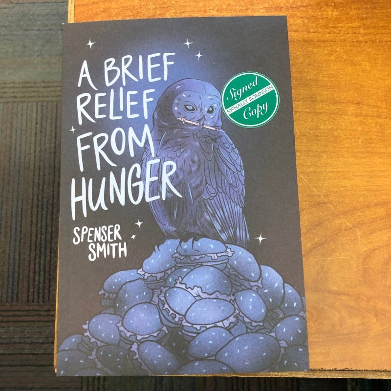 "A brief relief from hunger" on a wooden desk with a "signed copy" sticker.