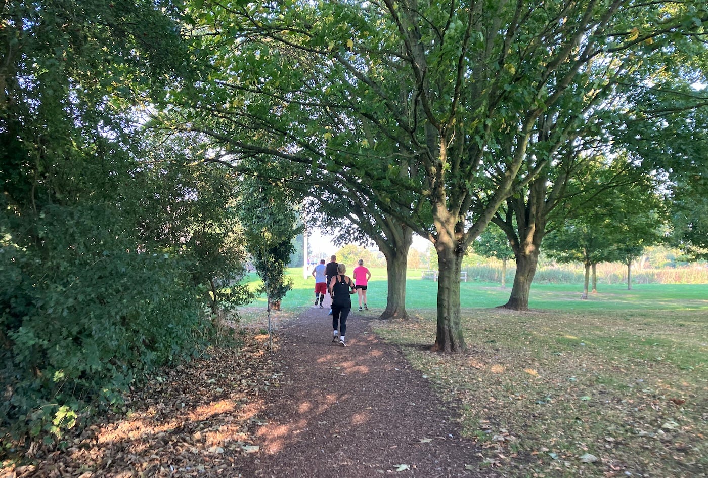 Runners on a hard mud path under shade