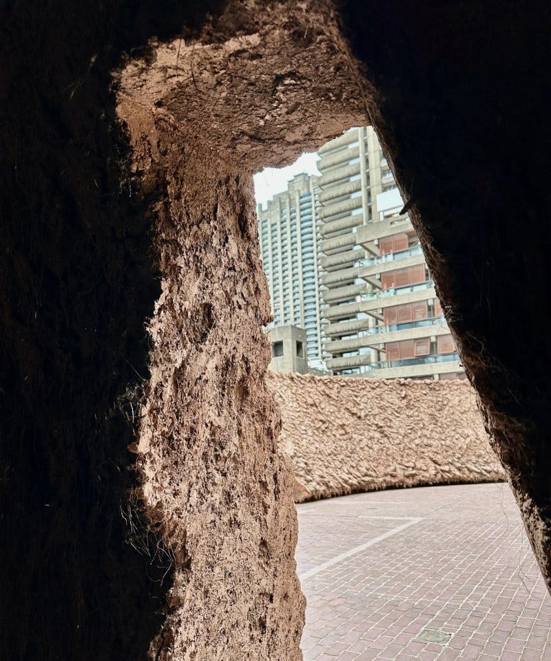 Looking out of the dark interior of Origo at its clay walls and the bricks of the world outside