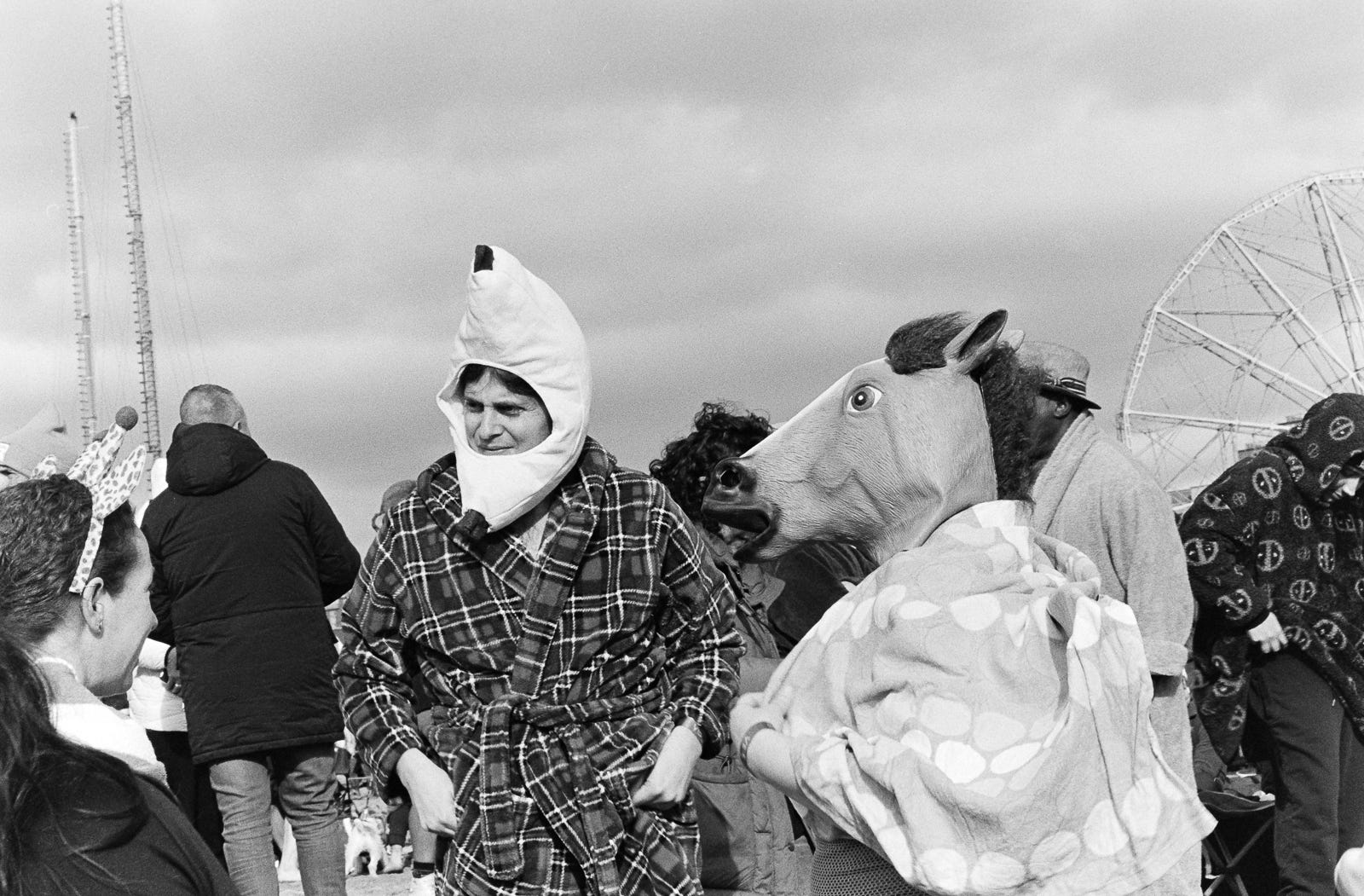 three people, one wearing a headband, another a banana costume around the face and a third wearing a horse head mask. 