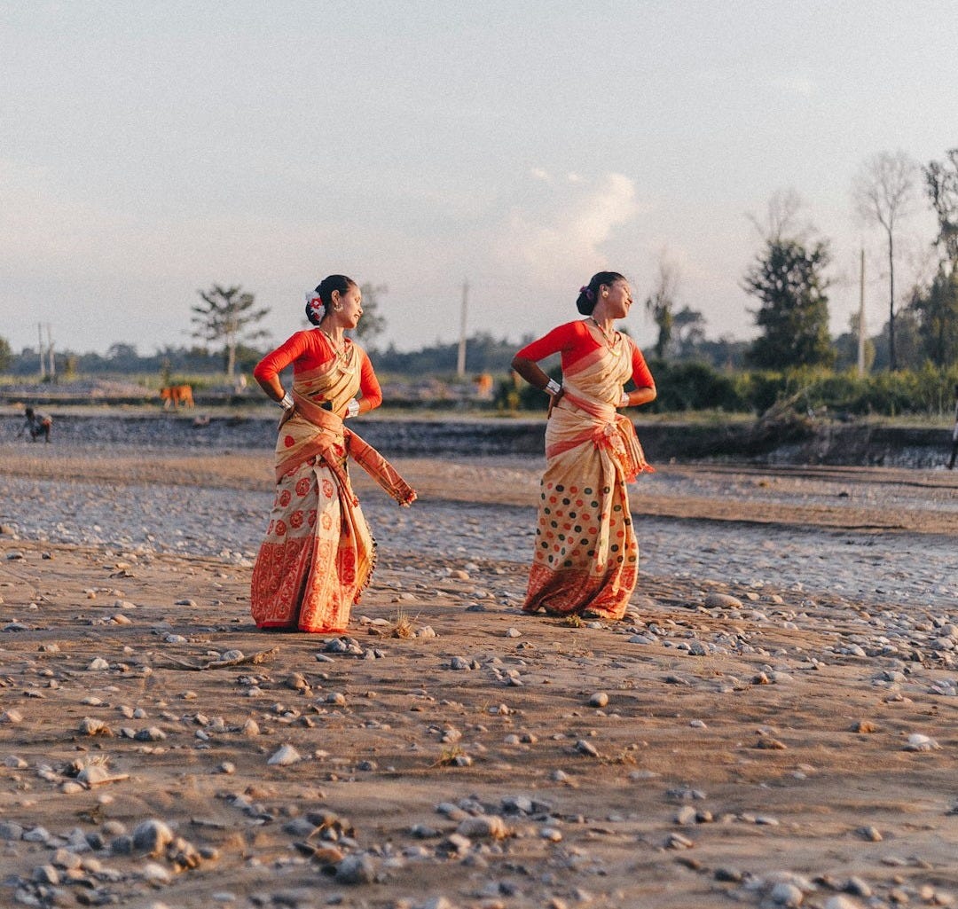 2 women walking on brown sand near body of water during daytime 2 women walking on brown sand near body of water during daytime