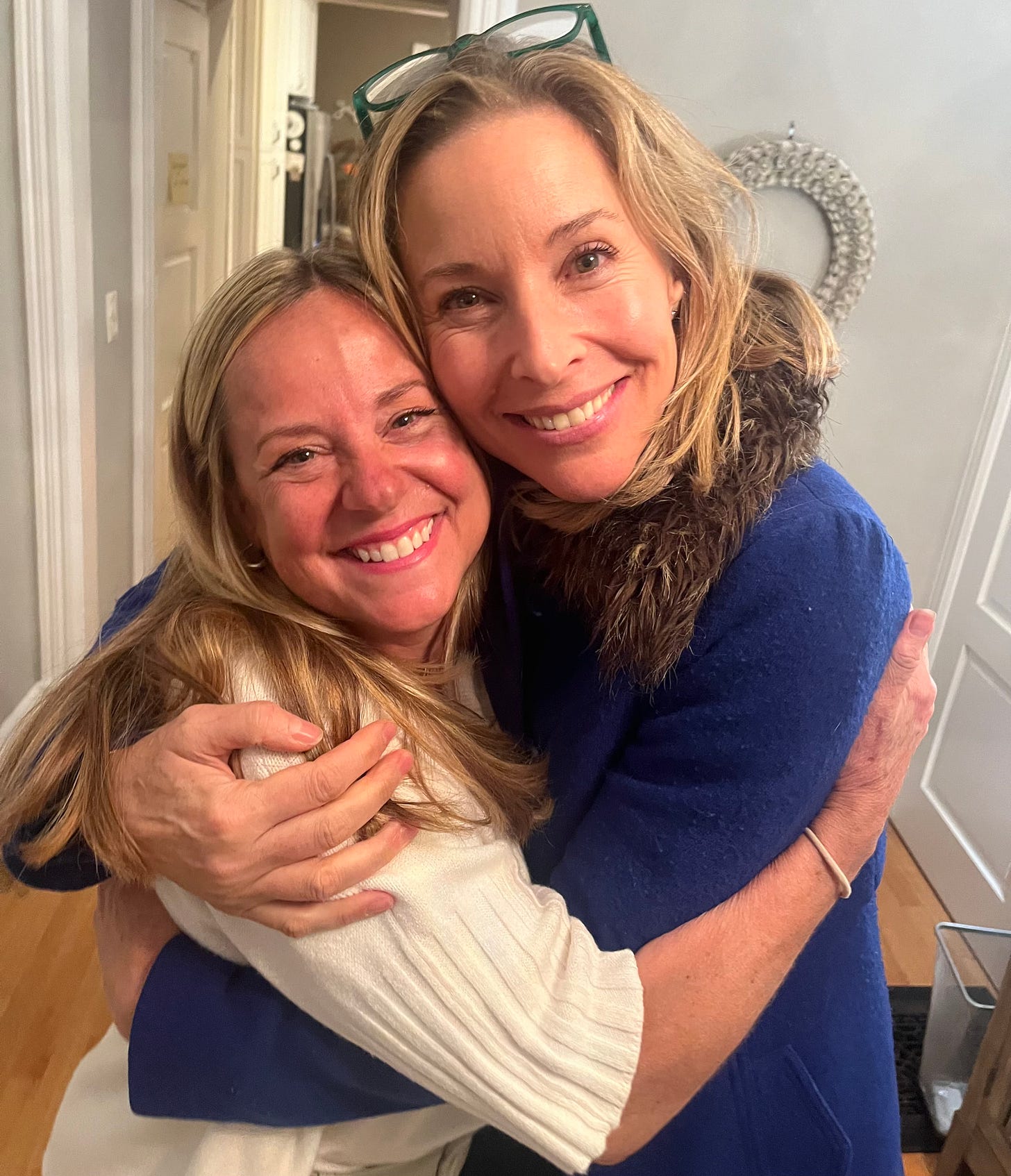 Two blonde women (one short, one tall) hug