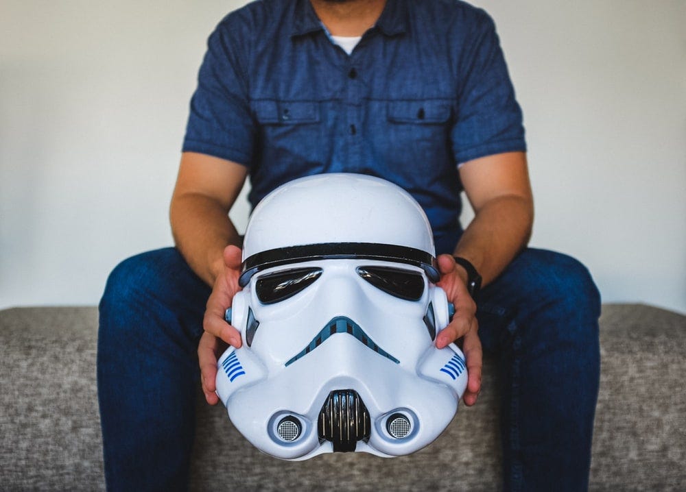 person sitting on sofa holding Stormtrooper helmet person sitting on sofa holding Stormtrooper helmet