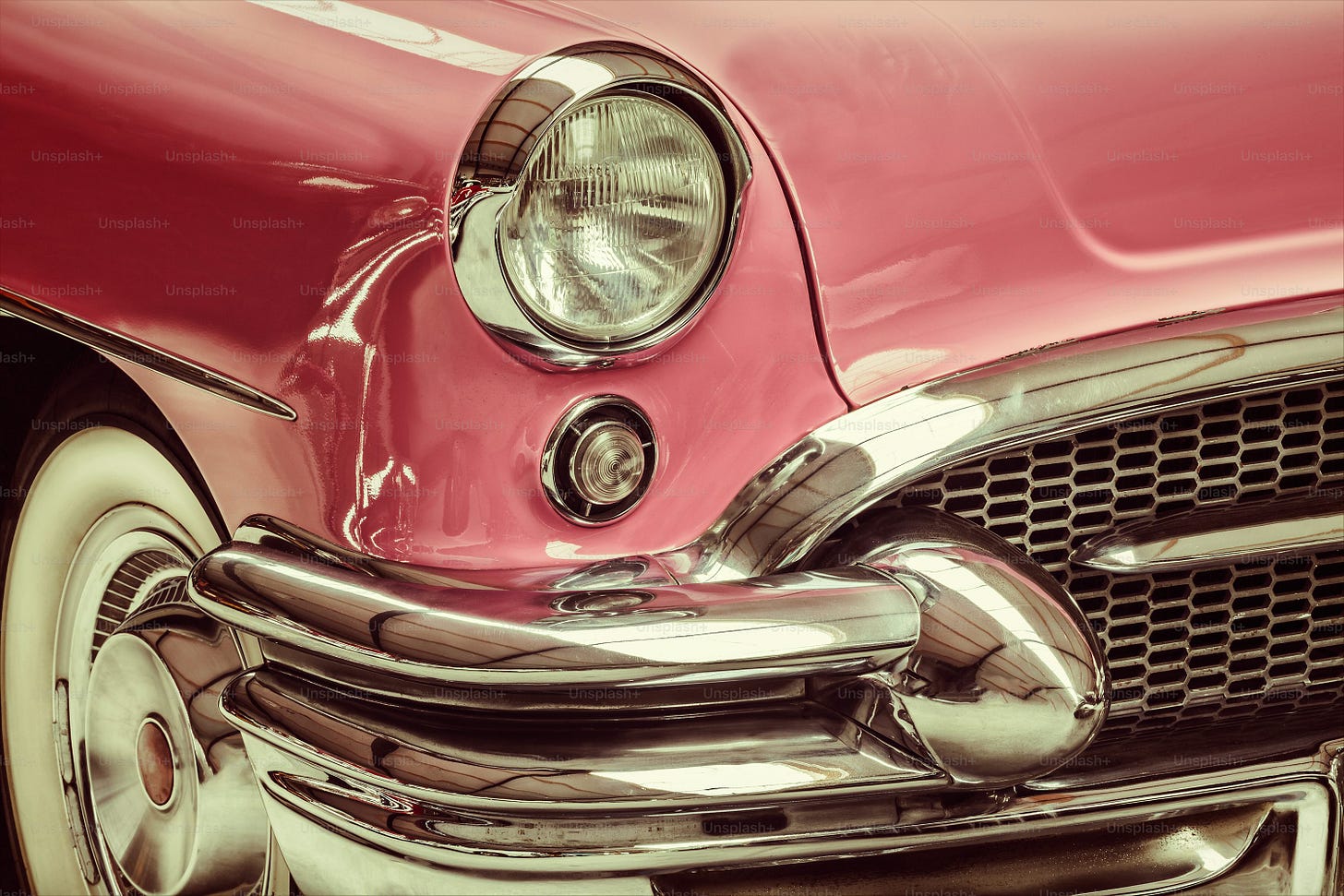 Retro styled image of a front of a pink classic car Retro styled image of a front of a pink classic car