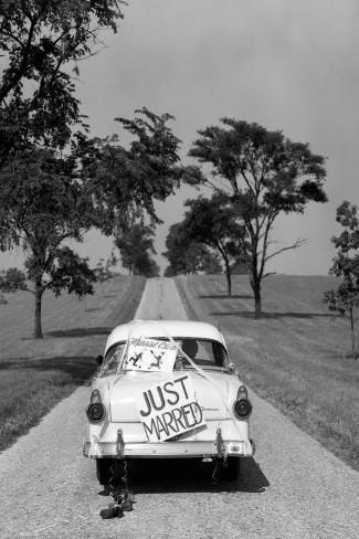 This may contain: an old car with just married written on it parked in the middle of a dirt road