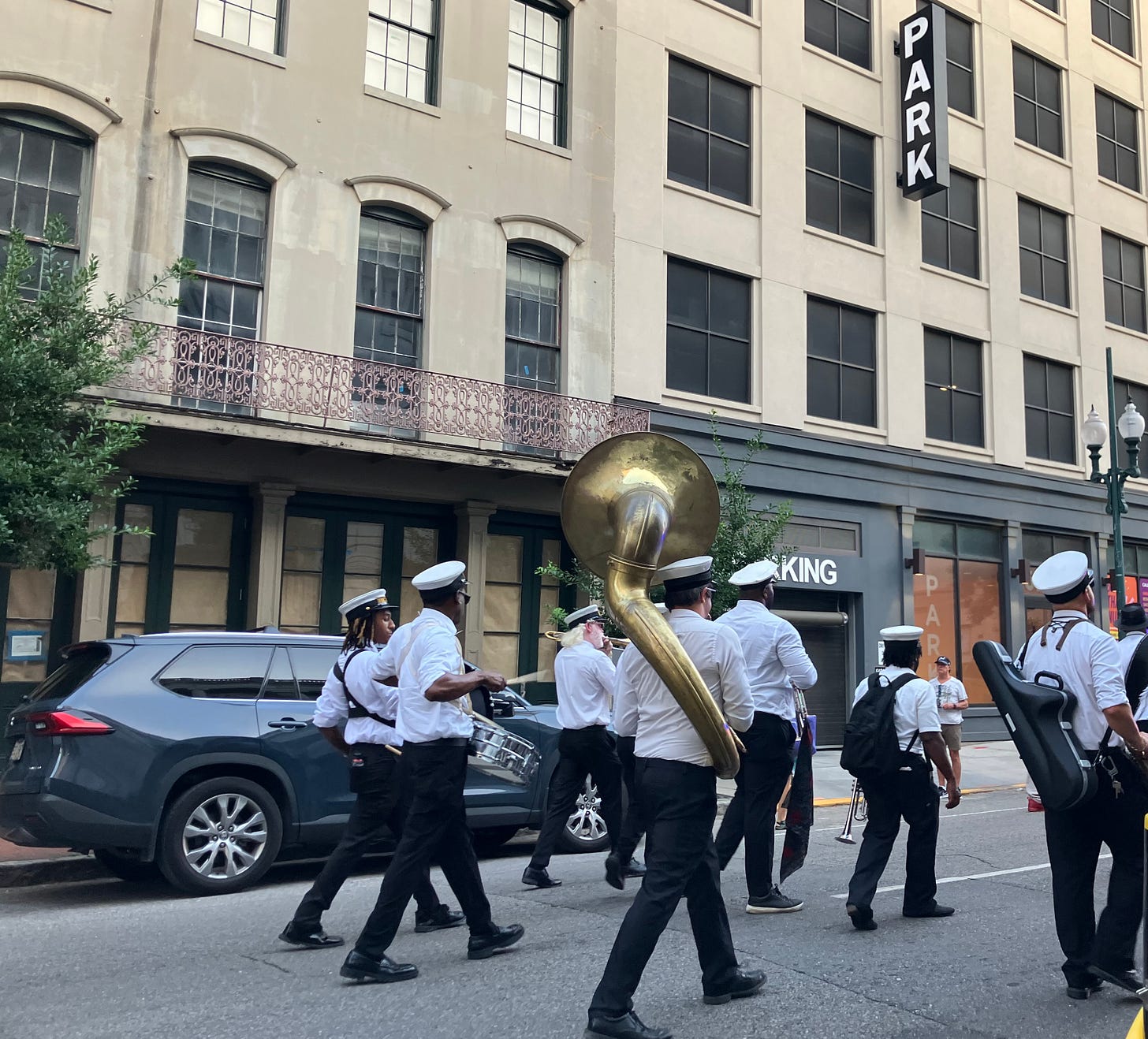 photo of second line parade playing music down middle of Magazine Street