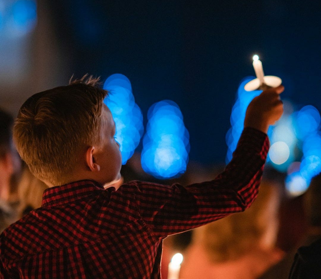 a young boy holding a toy airplane in front of a crowd of people a young boy holding a toy airplane in front of a crowd of people