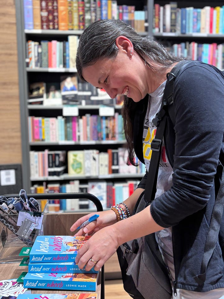 The author signing copies of Head Over Wheels and the books sitting on the shelves