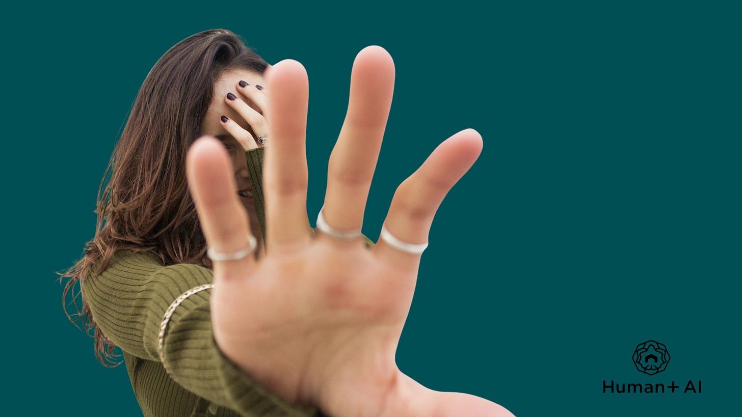 A woman blocks a camera from seeing her face with her hands
