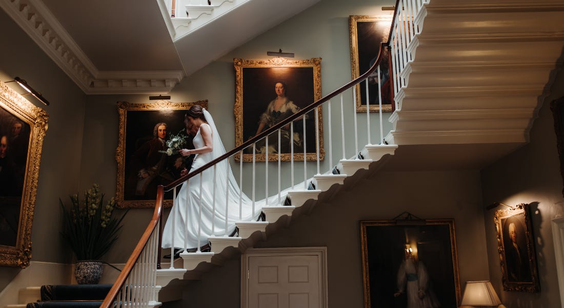 A staircase with gold framed pictures and a bride walking down A staircase with gold framed pictures and a bride walking down