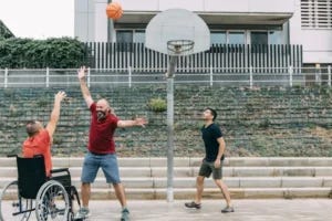 Man in a wheelchair shoots a basket against friends in a basketball game