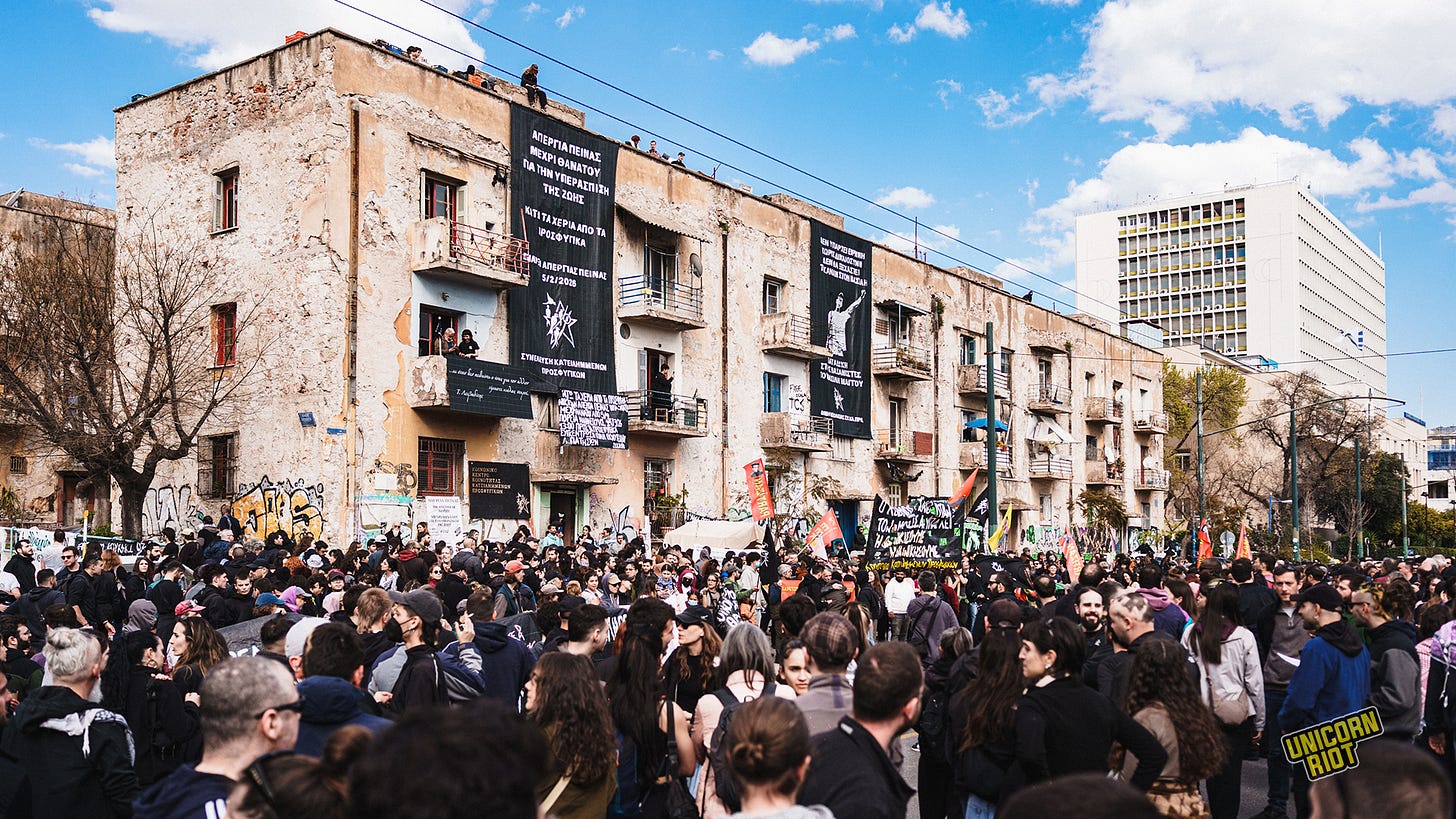Crowd outside a building in Greece with a massive banner with Greek hanging down it Crowd outside a building in Greece with a massive banner with Greek hanging down it