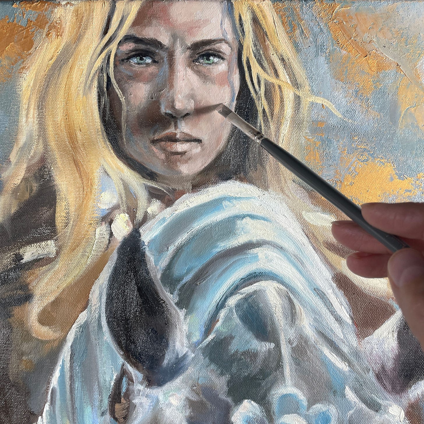 Painting of a blonde woman with green eyes, being detailed by a hand holding a small brush. Background features gold and blue hues. Detail of a painting by Kindrie Grove