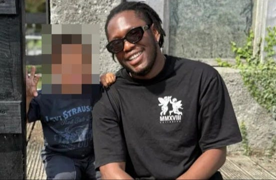 A man wearing sunglasses and a black t-shirt smiles next to a young child whose face is blurred. A man wearing sunglasses and a black t-shirt smiles next to a young child whose face is blurred.