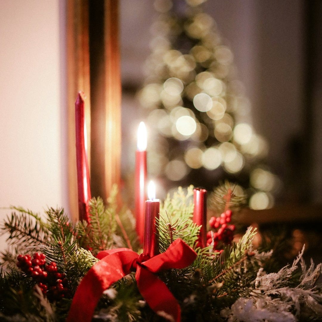 Advent wreath with lit candles and christmas tree reflection